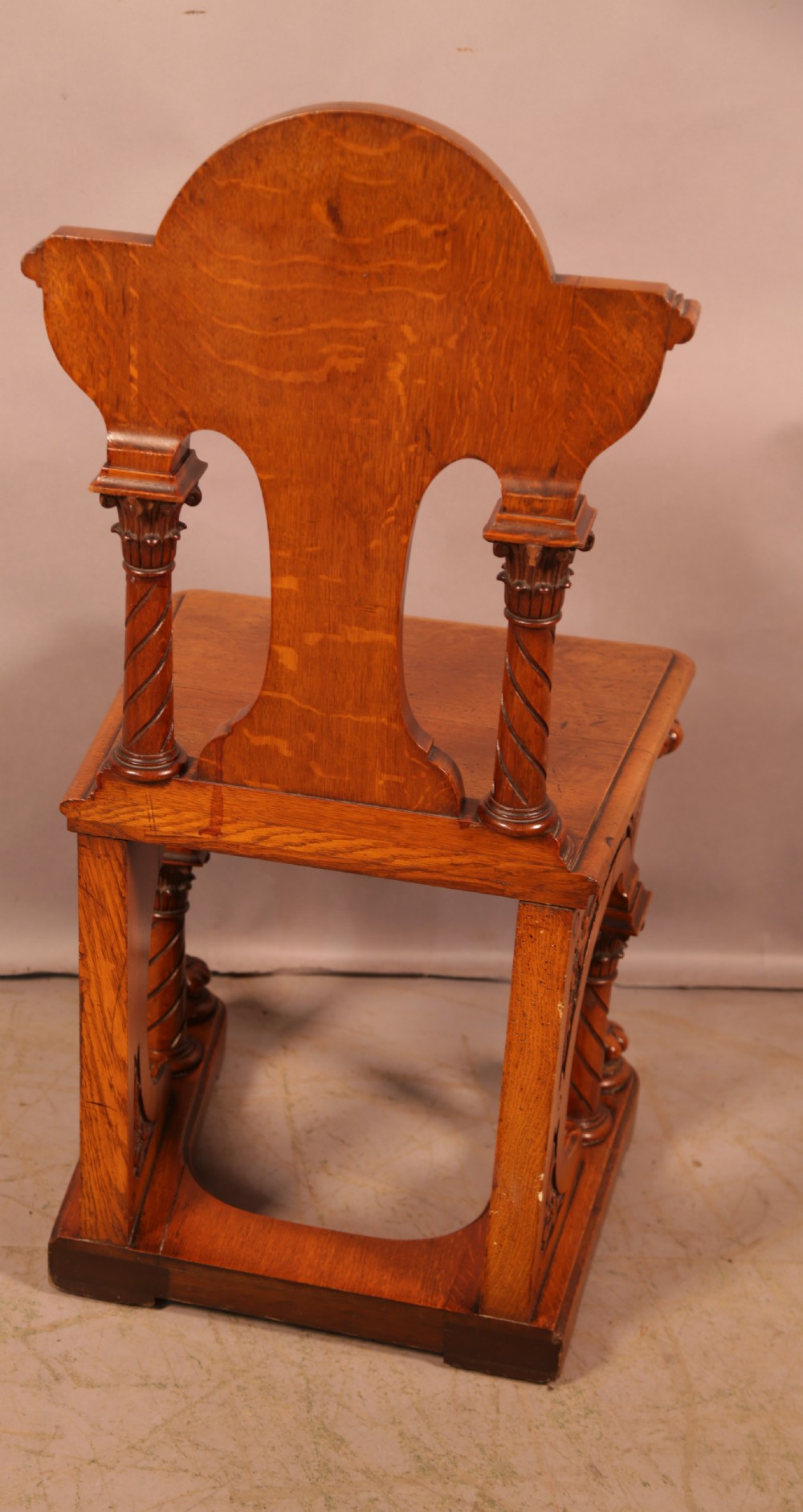 A matching pair of carved oak Victorian hall chairs featuring architectural columns and scrollwork crests. View V