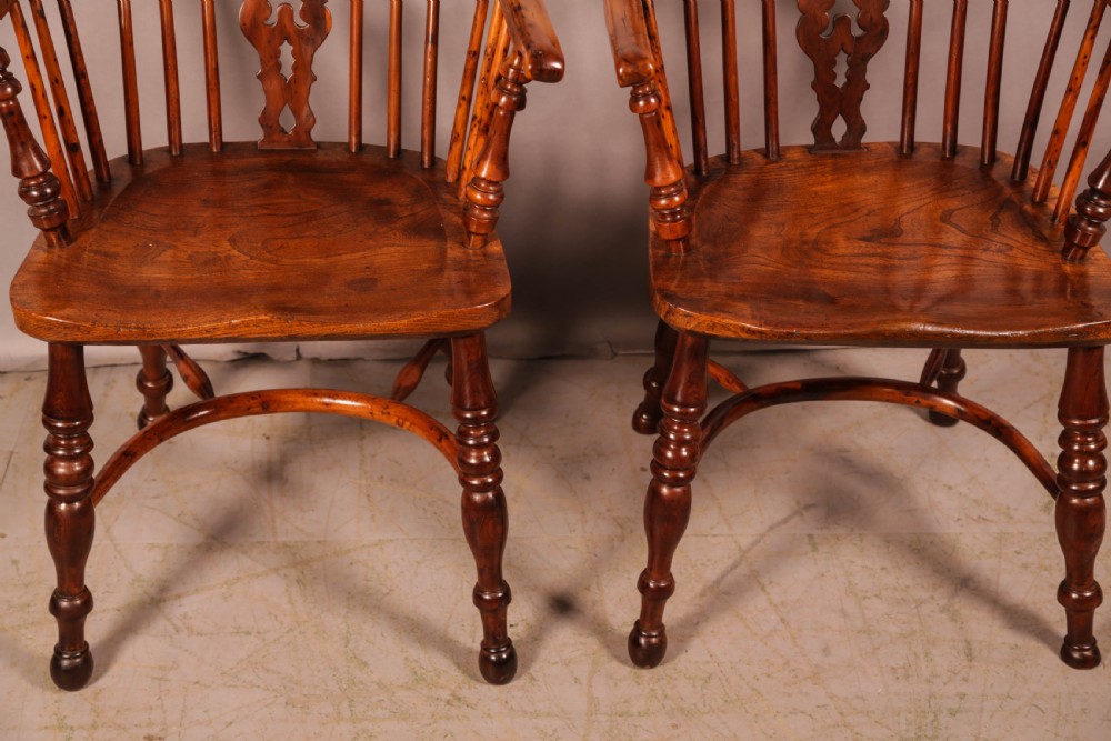 A pair of antique wooden Windsor armchairs featuring pierced splats, spindle backs, and turned legs with rich brown grain. View II