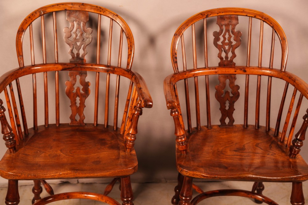 A pair of antique wooden Windsor armchairs featuring pierced splats, spindle backs, and turned legs with rich brown grain. View III