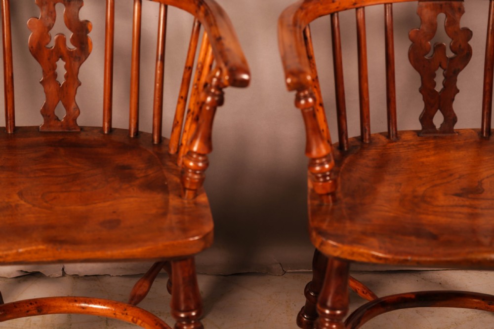 A pair of antique wooden Windsor armchairs featuring pierced splats, spindle backs, and turned legs with rich brown grain. View IV