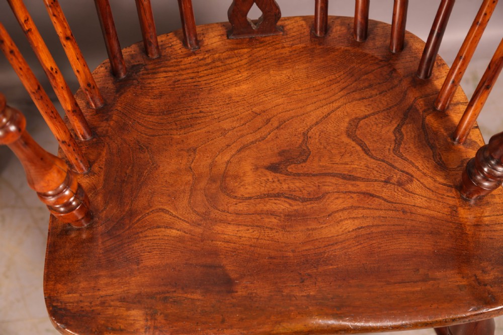 A pair of antique wooden Windsor armchairs featuring pierced splats, spindle backs, and turned legs with rich brown grain. View XI