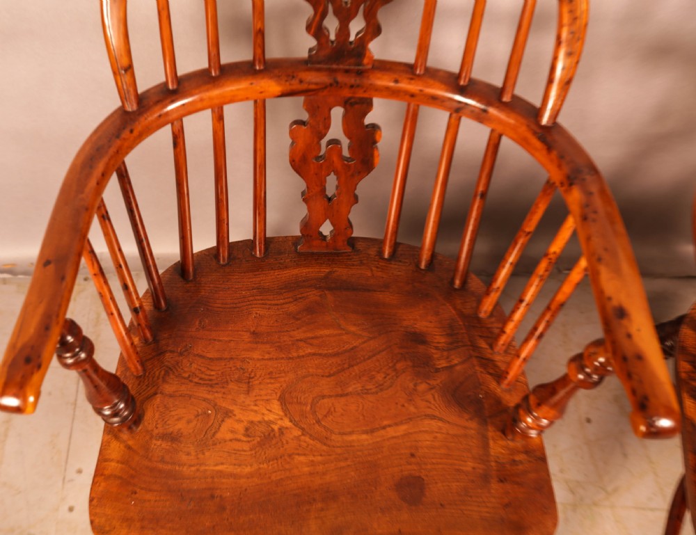 A pair of antique wooden Windsor armchairs featuring pierced splats, spindle backs, and turned legs with rich brown grain. View XII