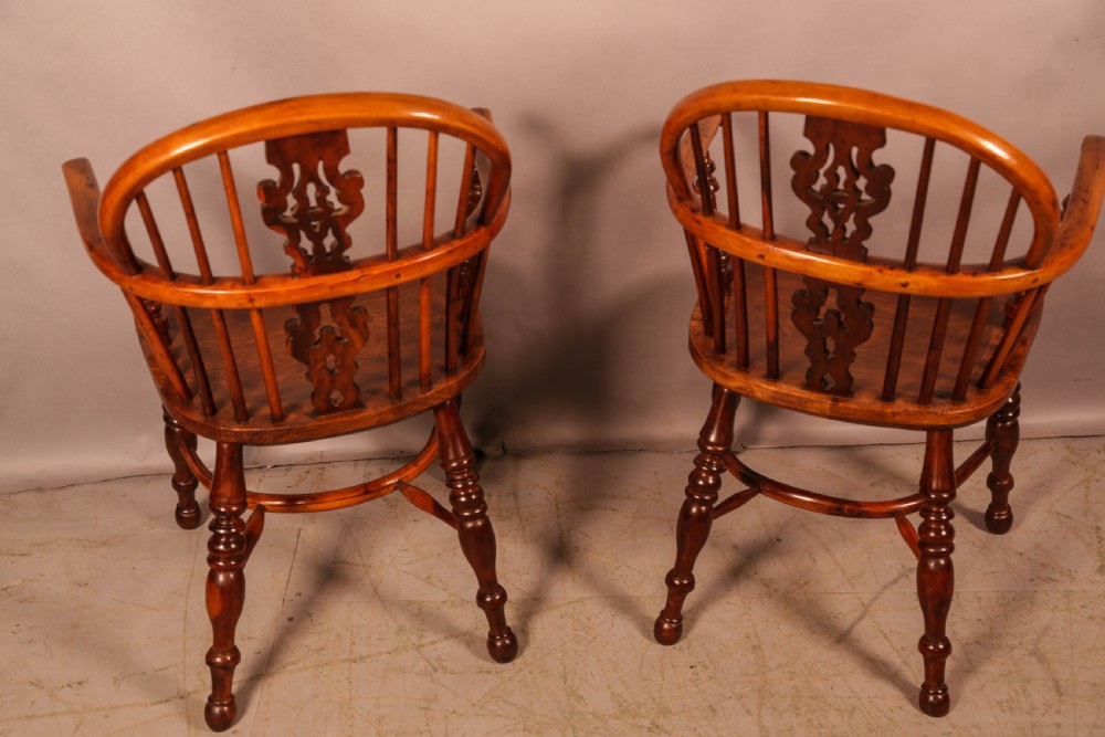 A pair of antique wooden Windsor armchairs featuring pierced splats, spindle backs, and turned legs with rich brown grain. View XV