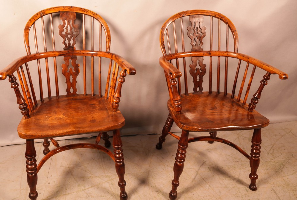 A pair of antique wooden Windsor armchairs featuring pierced splats, spindle backs, and turned legs with rich brown grain. View XX