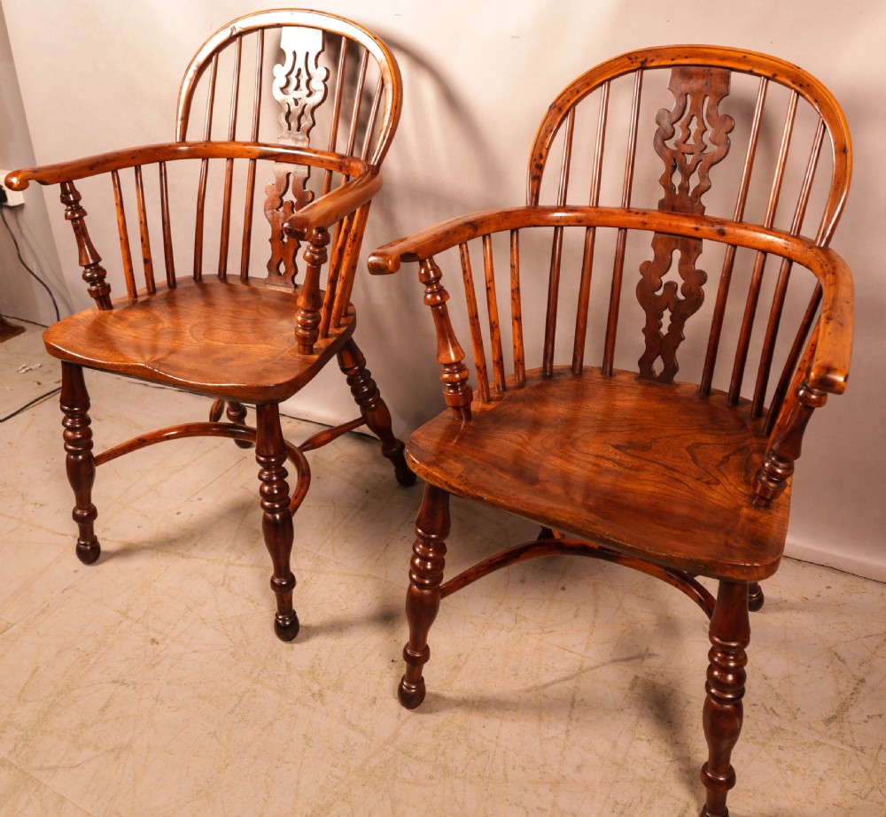 A pair of antique wooden Windsor armchairs featuring pierced splats, spindle backs, and turned legs with rich brown grain. View XXI