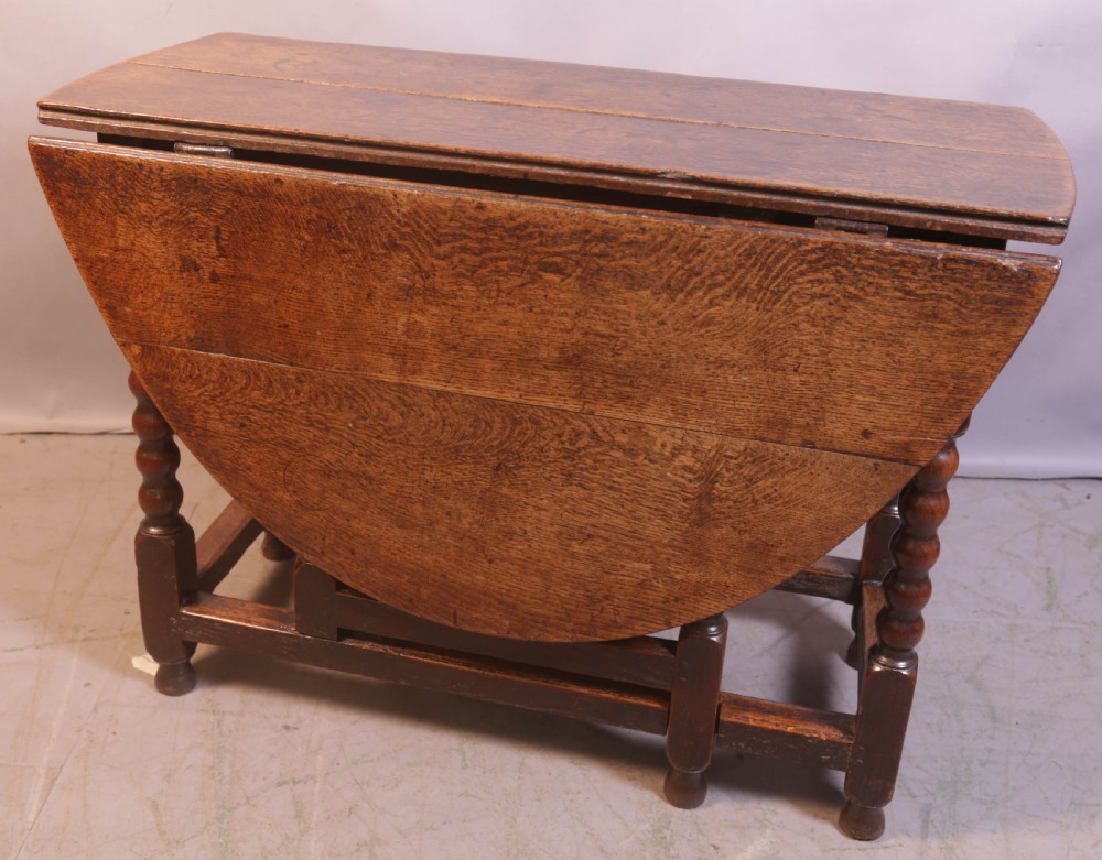 Seventeenth-century oak gateleg table featuring drop-leaf flaps, turned legs, and stretchers.