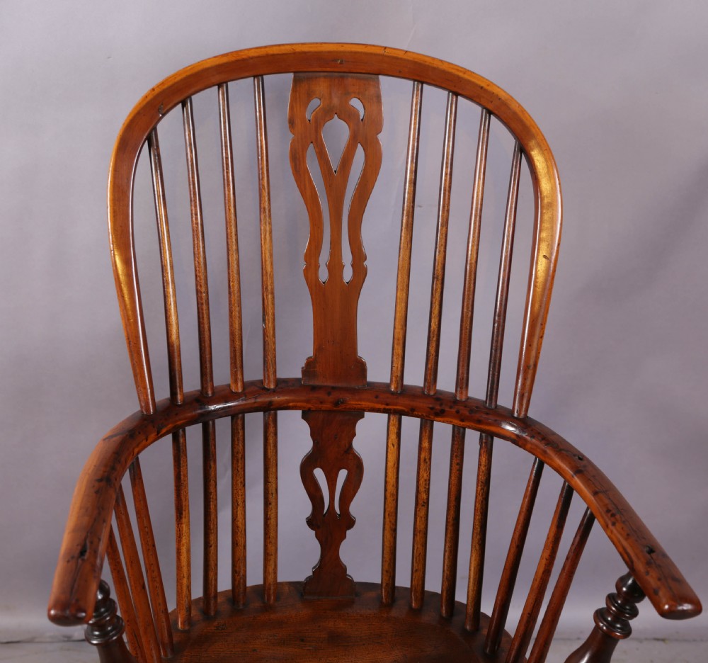An antique yew wood high back Windsor armchair featuring a pierced central splat, spindled hoop back, turned legs, and a solid shaped seat. View IV