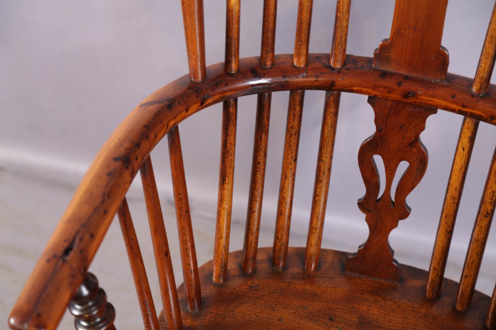 An antique yew wood high back Windsor armchair featuring a pierced central splat, spindled hoop back, turned legs, and a solid shaped seat. View VI