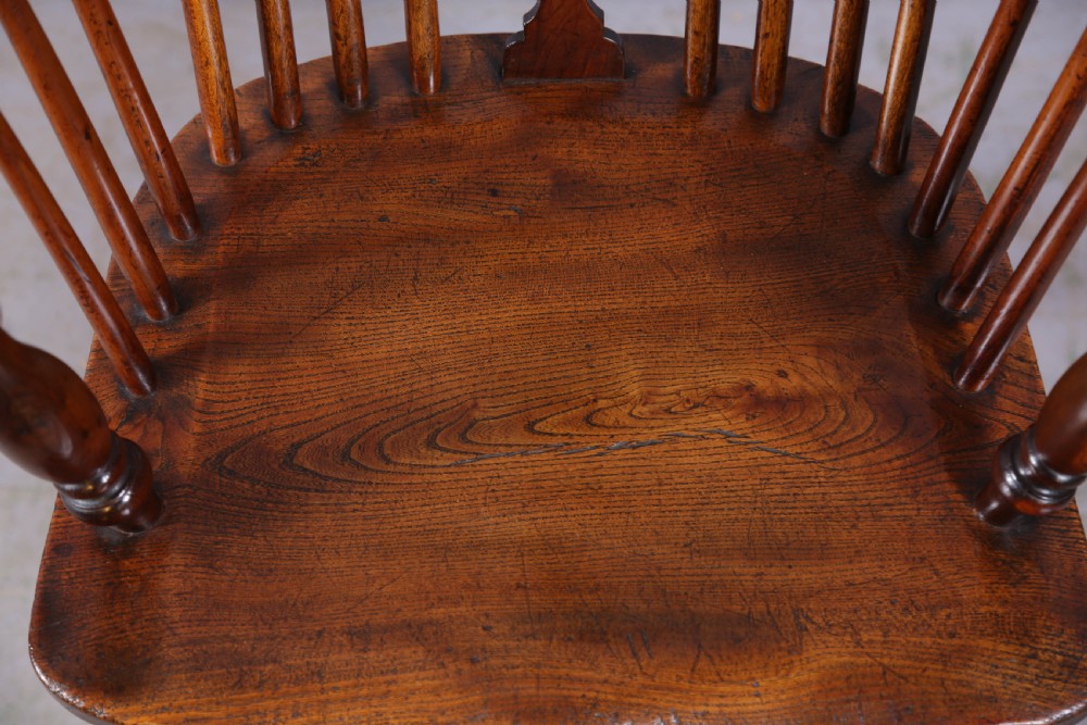 An antique yew wood high back Windsor armchair featuring a pierced central splat, spindled hoop back, turned legs, and a solid shaped seat. View VIII