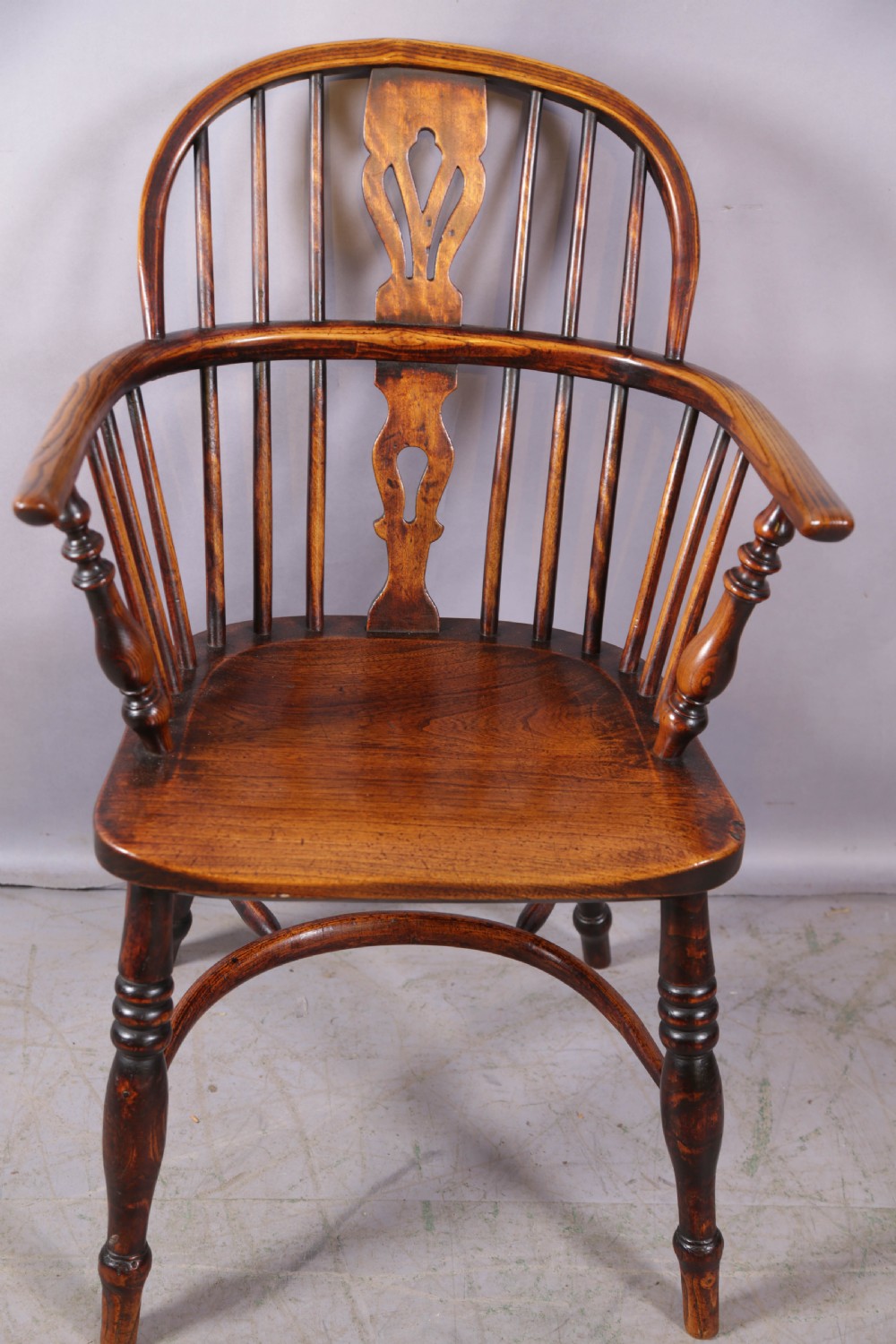 An antique ash and elm Windsor armchair featuring a steam-bent hoop back, pierced splat, turned legs, and a crinoline stretcher. View II