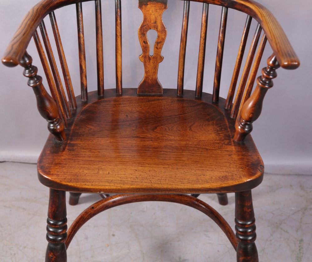 An antique ash and elm Windsor armchair featuring a steam-bent hoop back, pierced splat, turned legs, and a crinoline stretcher. View V