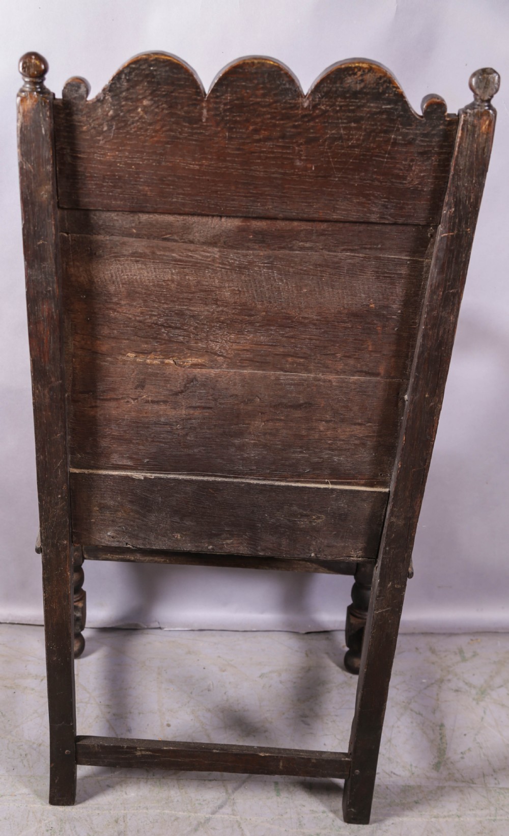 A dark oak wainscot chair featuring a carved panelled backrest, shaped scrolled arms, and turned front legs. View VIII