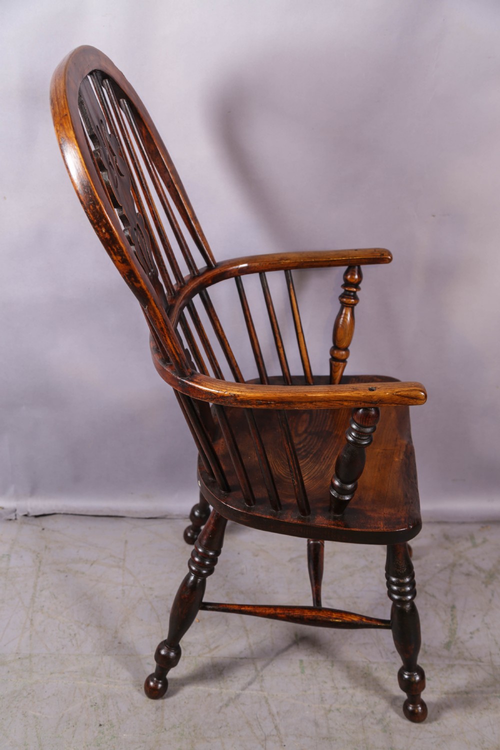 An antique high-back wooden Windsor armchair crafted from ash and elm with a pierced central splat, turned legs, and a shaped saddle seat. View II