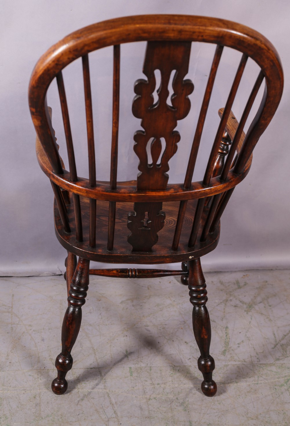 An antique high-back wooden Windsor armchair crafted from ash and elm with a pierced central splat, turned legs, and a shaped saddle seat. View III