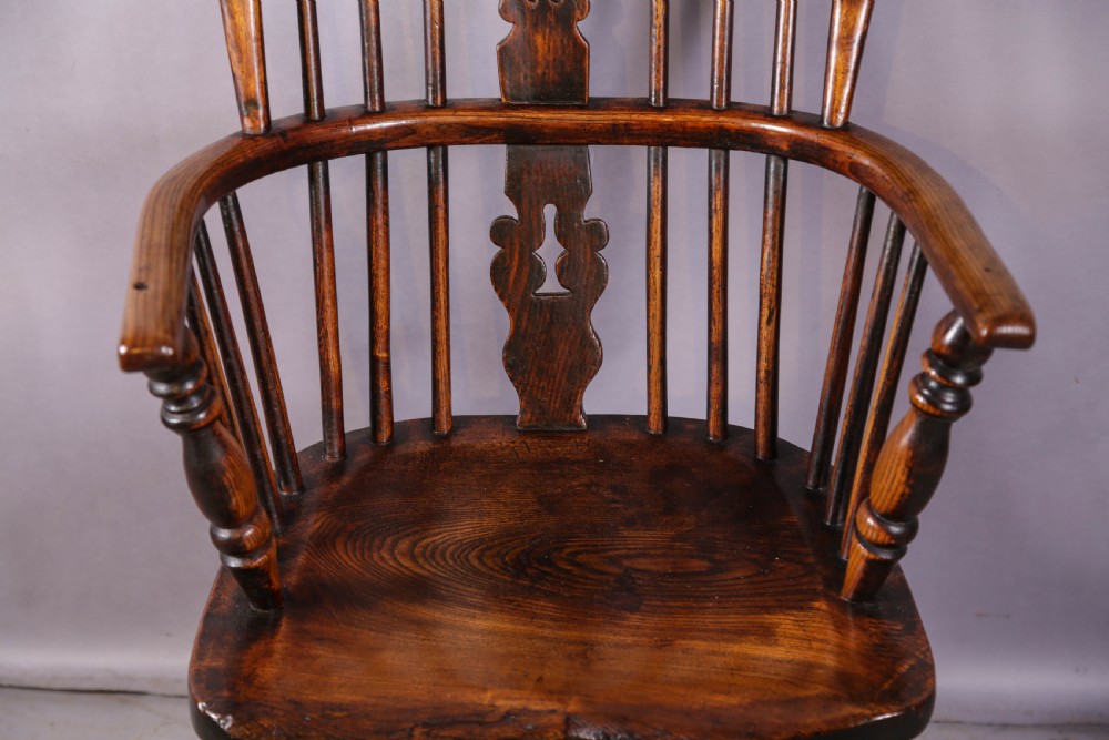 An antique high-back wooden Windsor armchair crafted from ash and elm with a pierced central splat, turned legs, and a shaped saddle seat. View IV