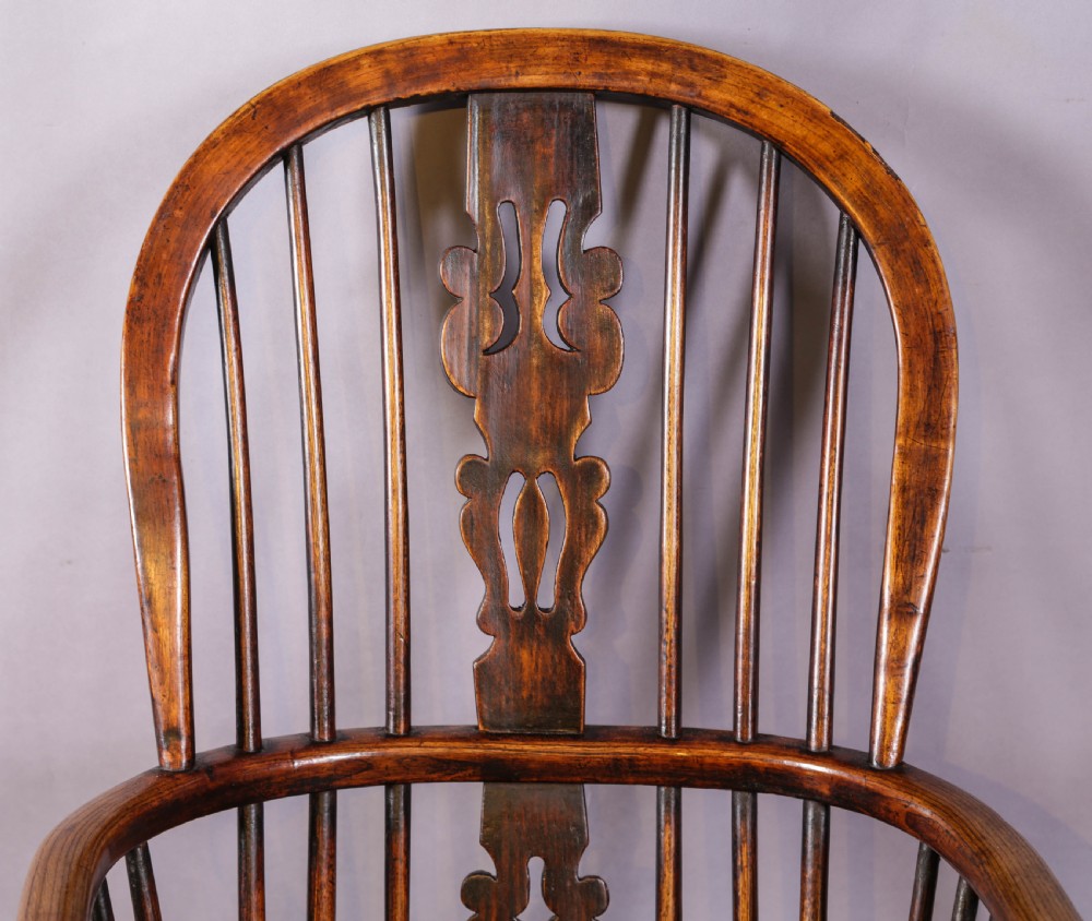 An antique high-back wooden Windsor armchair crafted from ash and elm with a pierced central splat, turned legs, and a shaped saddle seat. View V