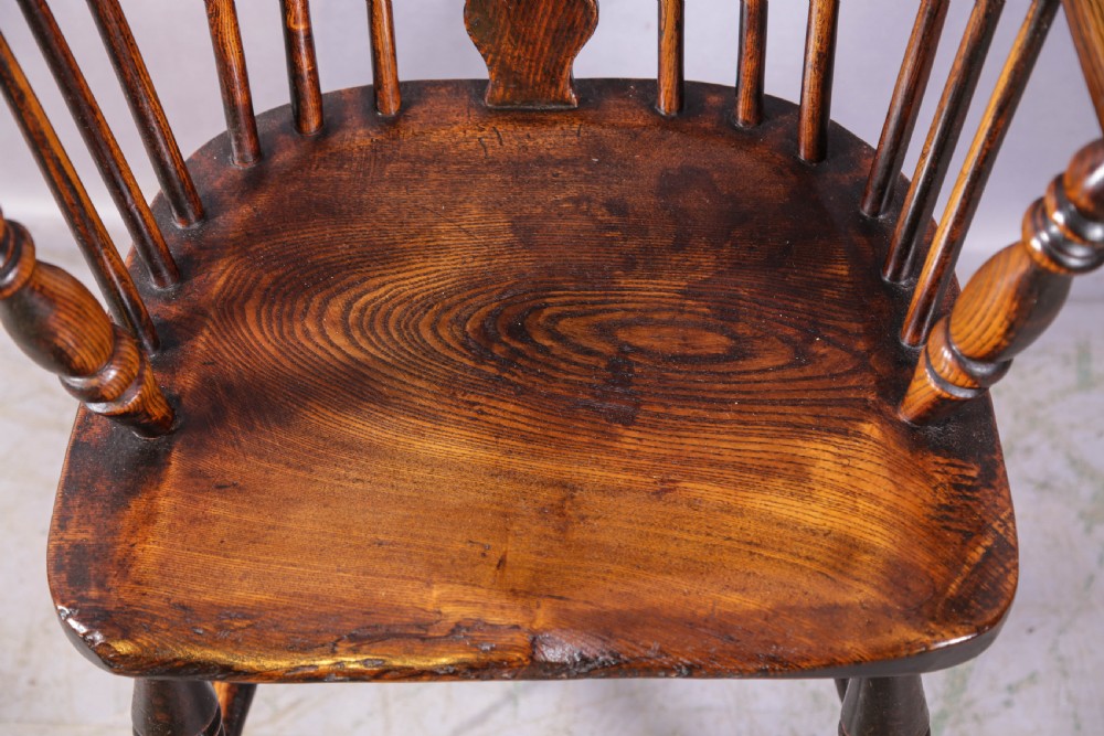 An antique high-back wooden Windsor armchair crafted from ash and elm with a pierced central splat, turned legs, and a shaped saddle seat. View VII