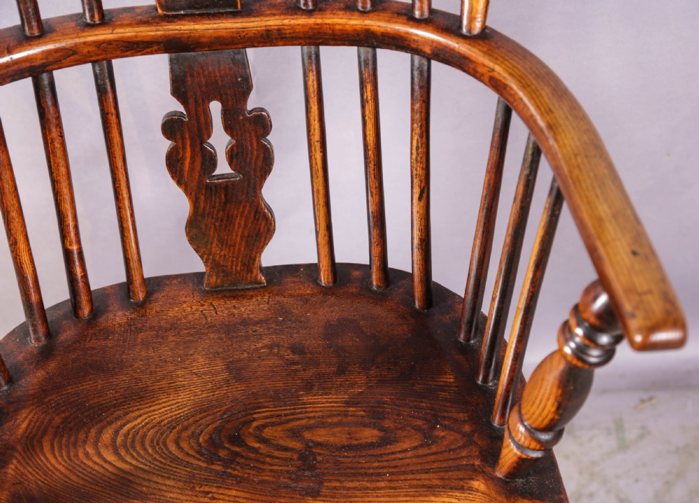 An antique high-back wooden Windsor armchair crafted from ash and elm with a pierced central splat, turned legs, and a shaped saddle seat. View IX