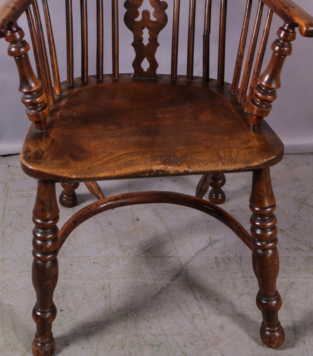 An antique yew wood Windsor armchair featuring a high hoop back, pierced fretwork central splat, turned legs, and a crinoline stretcher. View II
