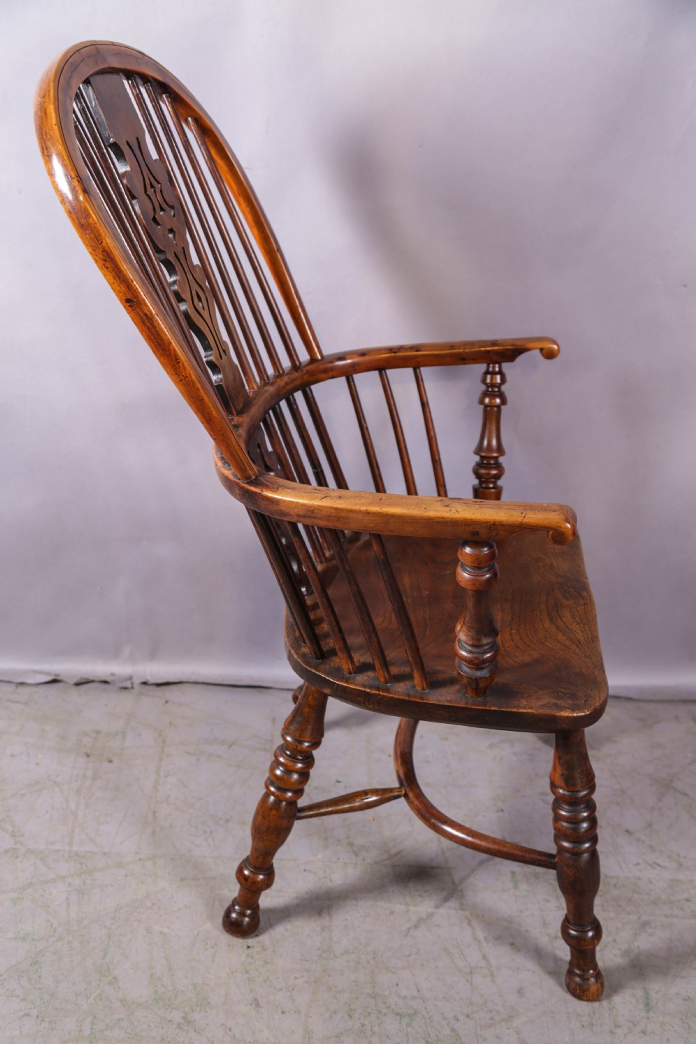 An antique yew wood Windsor armchair featuring a high hoop back, pierced fretwork central splat, turned legs, and a crinoline stretcher. View III