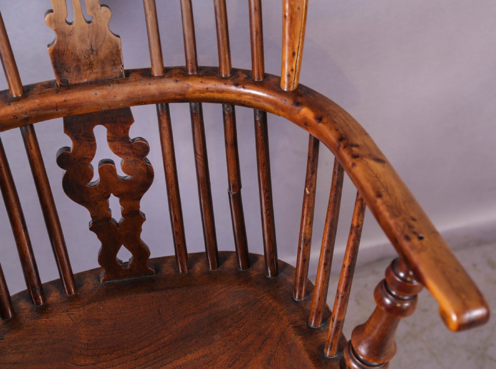 An antique yew wood Windsor armchair featuring a high hoop back, pierced fretwork central splat, turned legs, and a crinoline stretcher. View V