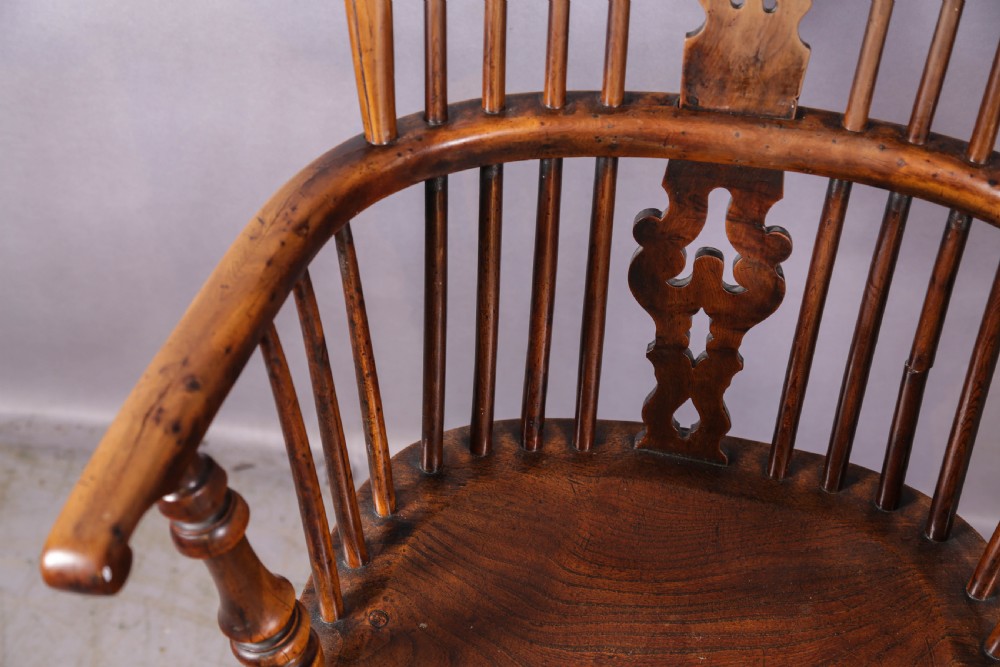 An antique yew wood Windsor armchair featuring a high hoop back, pierced fretwork central splat, turned legs, and a crinoline stretcher. View VI