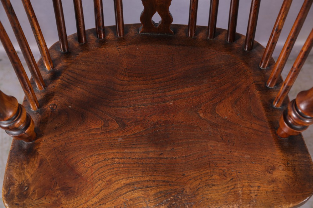 An antique yew wood Windsor armchair featuring a high hoop back, pierced fretwork central splat, turned legs, and a crinoline stretcher. View VII