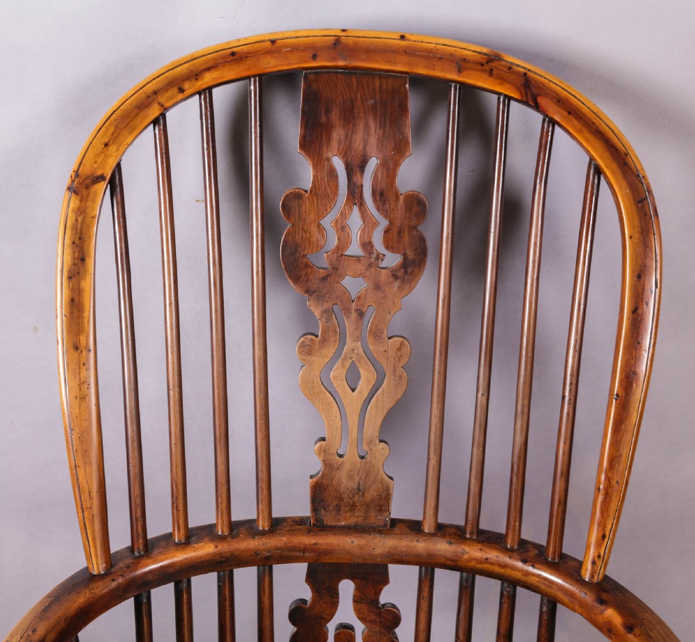 An antique yew wood Windsor armchair featuring a high hoop back, pierced fretwork central splat, turned legs, and a crinoline stretcher. View VIII