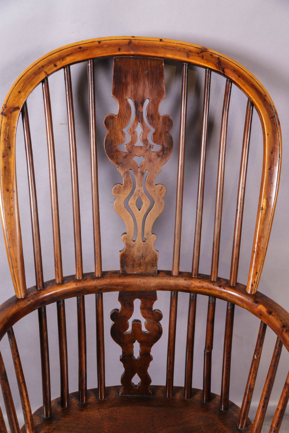 An antique yew wood Windsor armchair featuring a high hoop back, pierced fretwork central splat, turned legs, and a crinoline stretcher. View IX
