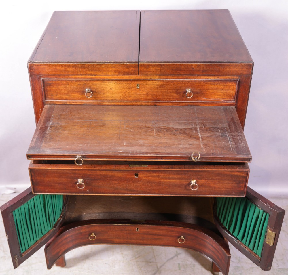 A Georgian mahogany gentlemans dressing chest featuring a split hinged top, brass ring handles, and a concave lower section with green fabric panels. View V