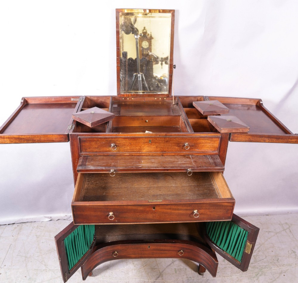 A Georgian mahogany gentlemans dressing chest featuring a split hinged top, brass ring handles, and a concave lower section with green fabric panels. View VIII