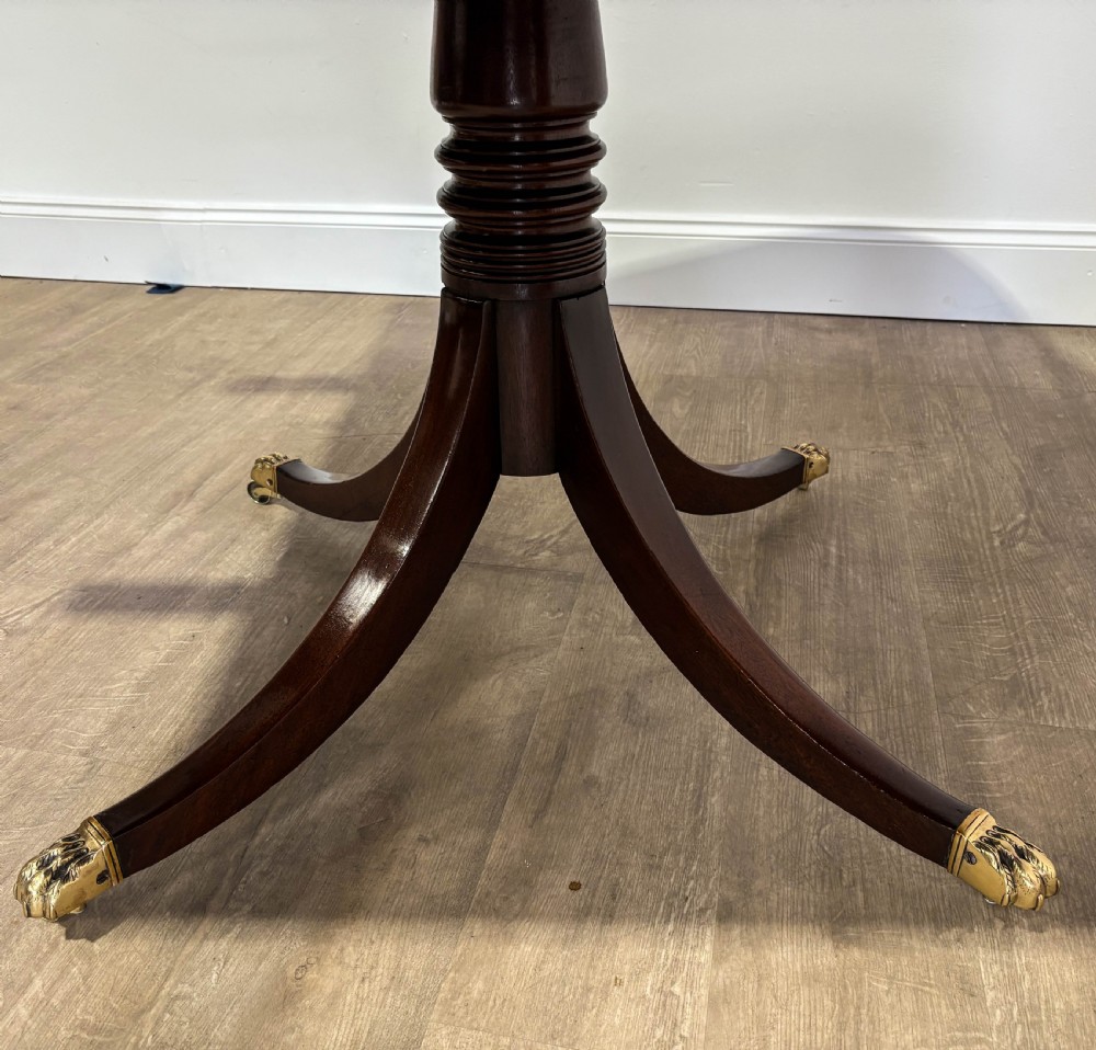 A large polished mahogany twin pedestal dining table with brass claw feet and extending leaves set on a wooden floor. View V