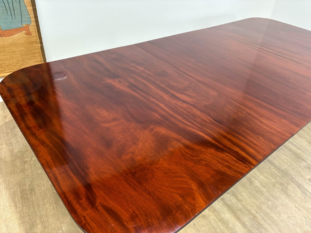A large polished mahogany twin pedestal dining table with brass claw feet and extending leaves set on a wooden floor. View XIII