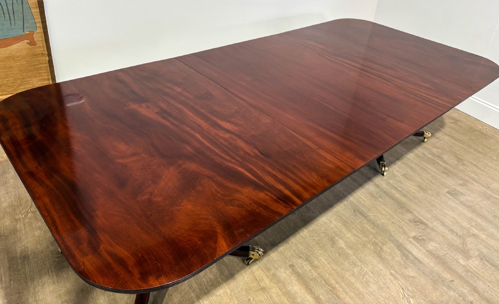 A large polished mahogany twin pedestal dining table with brass claw feet and extending leaves set on a wooden floor. View XXII