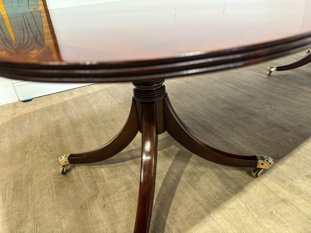 A large polished mahogany twin pedestal dining table with brass claw feet and extending leaves set on a wooden floor. View XXIV