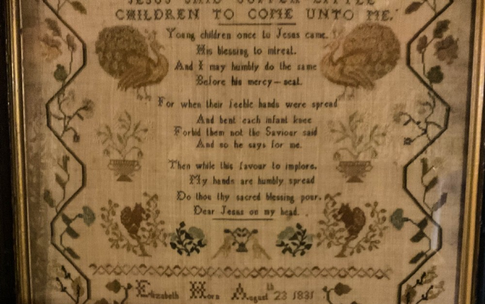 Framed 1831 needlework sampler featuring an embroidered alphabet, religious verse, peacocks, floral borders, and a signature dated August 23 1831. View X