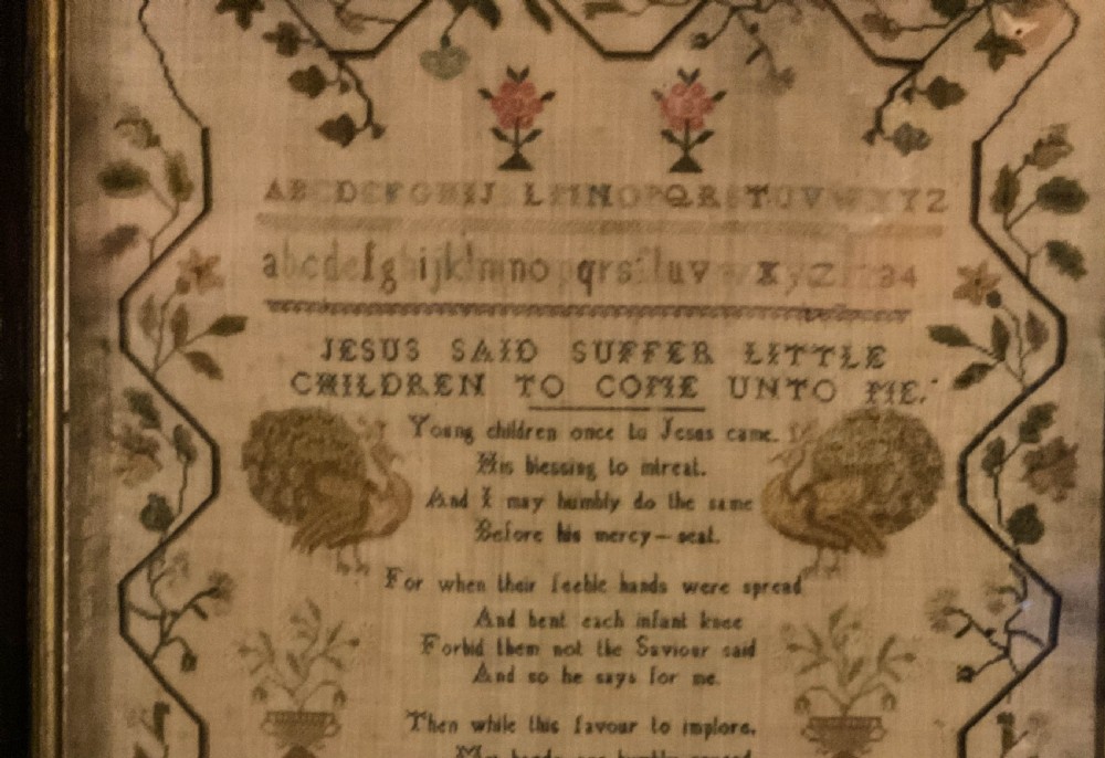 Framed 1831 needlework sampler featuring an embroidered alphabet, religious verse, peacocks, floral borders, and a signature dated August 23 1831. View XI
