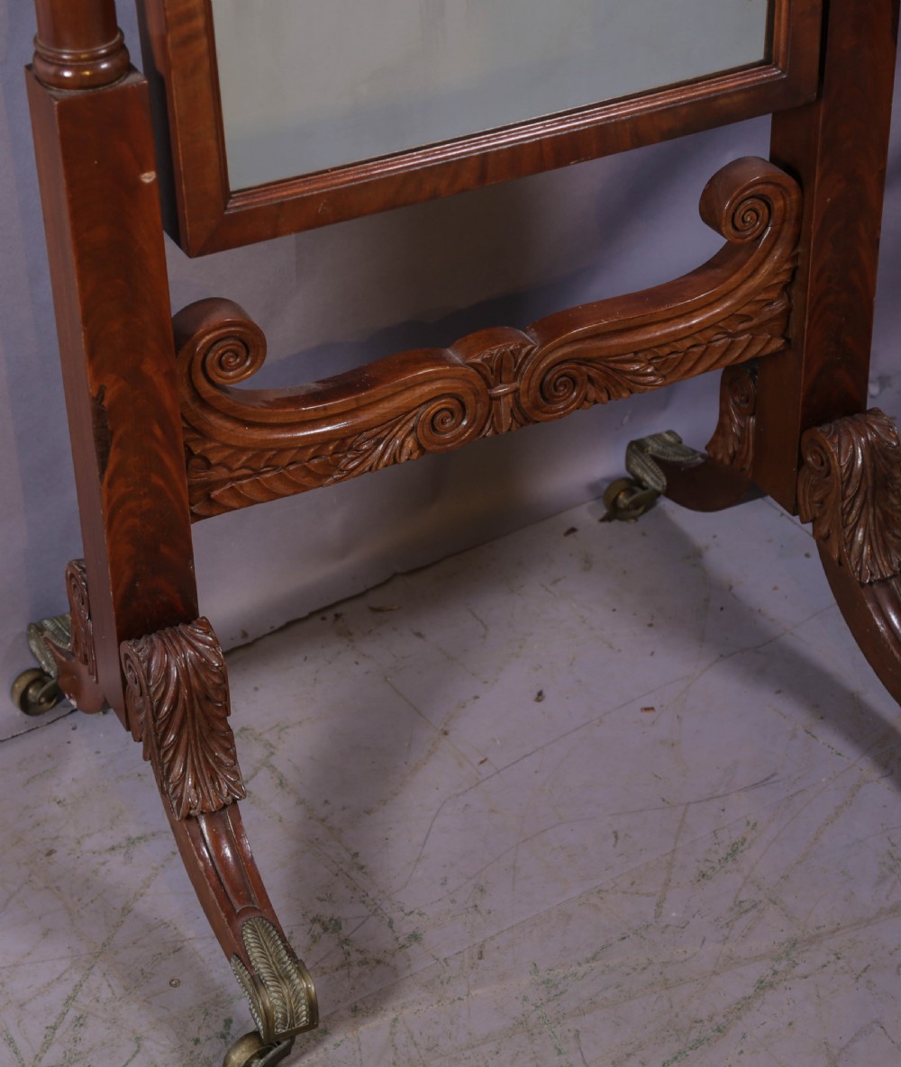 An American Empire mahogany cheval mirror with turned side columns, a pedimented top, brass mounts, and a carved scroll base with paw feet. View VI