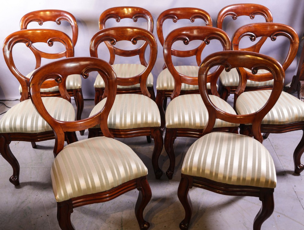 A set of ten Victorian mahogany dining chairs featuring characteristic balloon backrests and striped upholstery on cabriole legs.