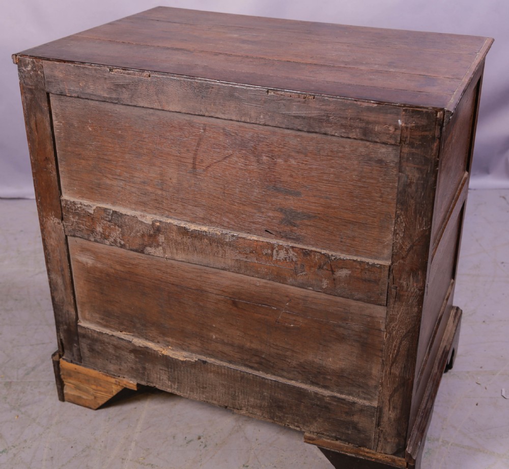 An early 18th-century dark oak chest of drawers featuring geometric moulding on the drawer fronts and brass drop handles. View X