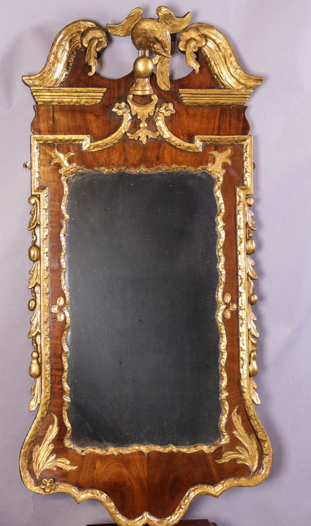 An 18th-century pier glass featuring a walnut veneer frame with elaborate giltwood carvings, scroll pediment, and a central carved eagle cresting. View V