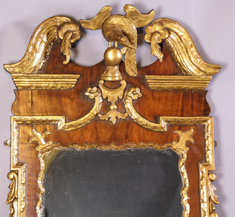 An 18th-century pier glass featuring a walnut veneer frame with elaborate giltwood carvings, scroll pediment, and a central carved eagle cresting. View VI