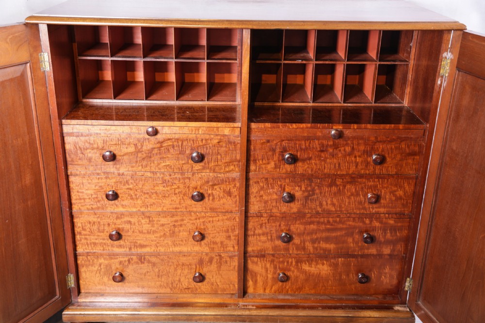 A 19th-century flame mahogany two-door estate cabinet with carved spandrel mouldings and turned bun feet. View V