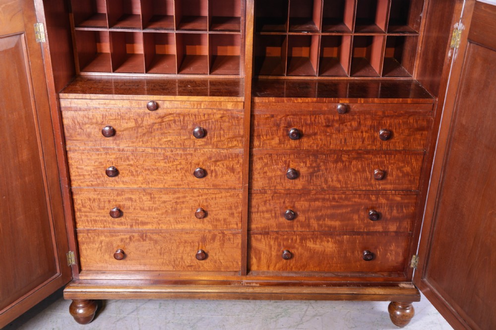 A 19th-century flame mahogany two-door estate cabinet with carved spandrel mouldings and turned bun feet. View VI
