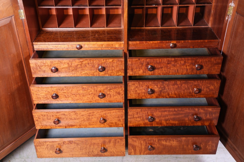 A 19th-century flame mahogany two-door estate cabinet with carved spandrel mouldings and turned bun feet. View XI