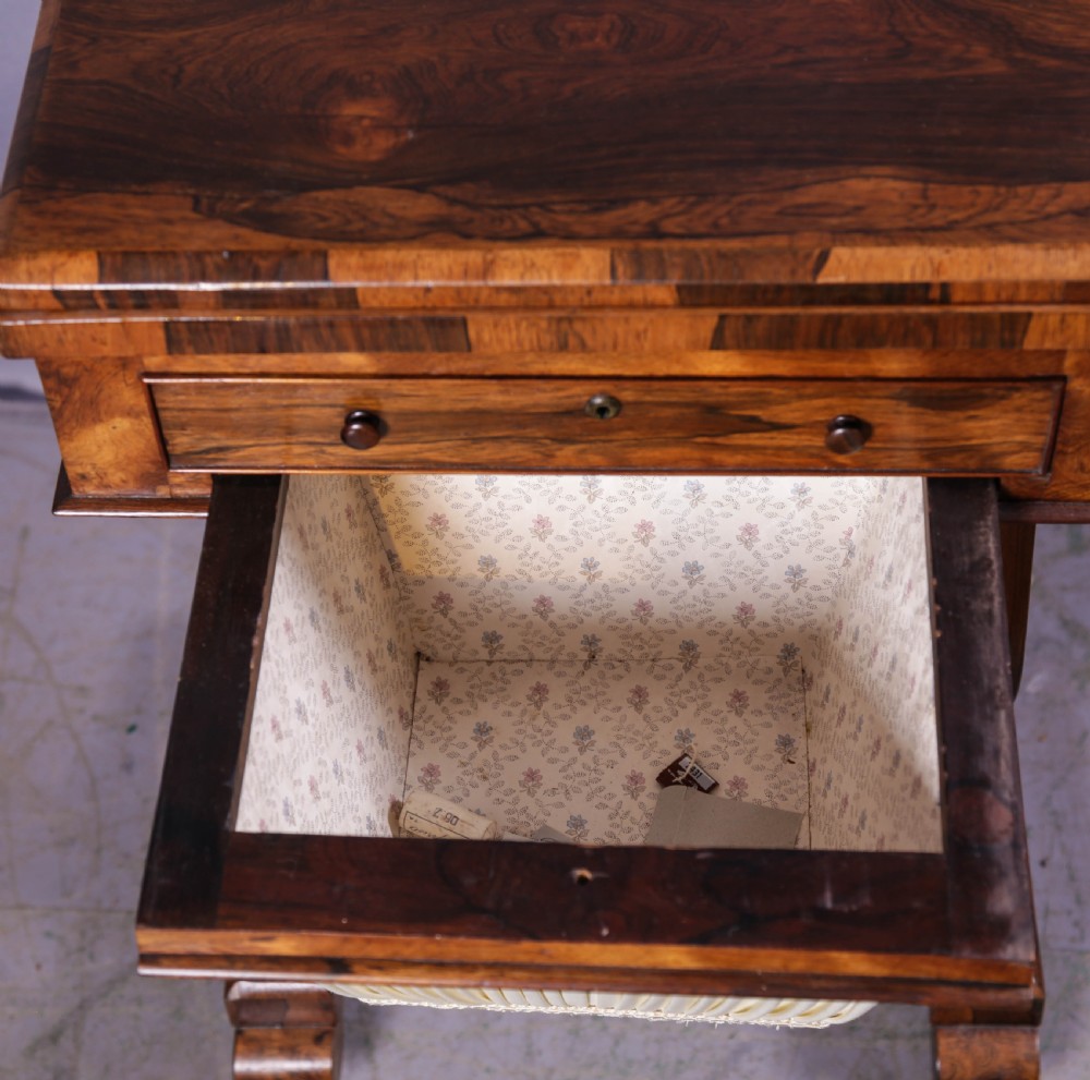 A Victorian rosewood sewing and games table featuring a fold-over top, a single frieze drawer, and a suspended pleated fabric work bag supported by a lyre-form pedestal base with brass castors. View VII