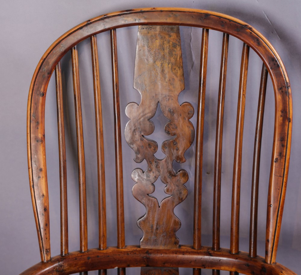 An antique yew wood high back Windsor armchair featuring a bow back, pierced central splat, shaped saddle seat, turned arm supports, turned legs, and a crinoline stretcher. View VII