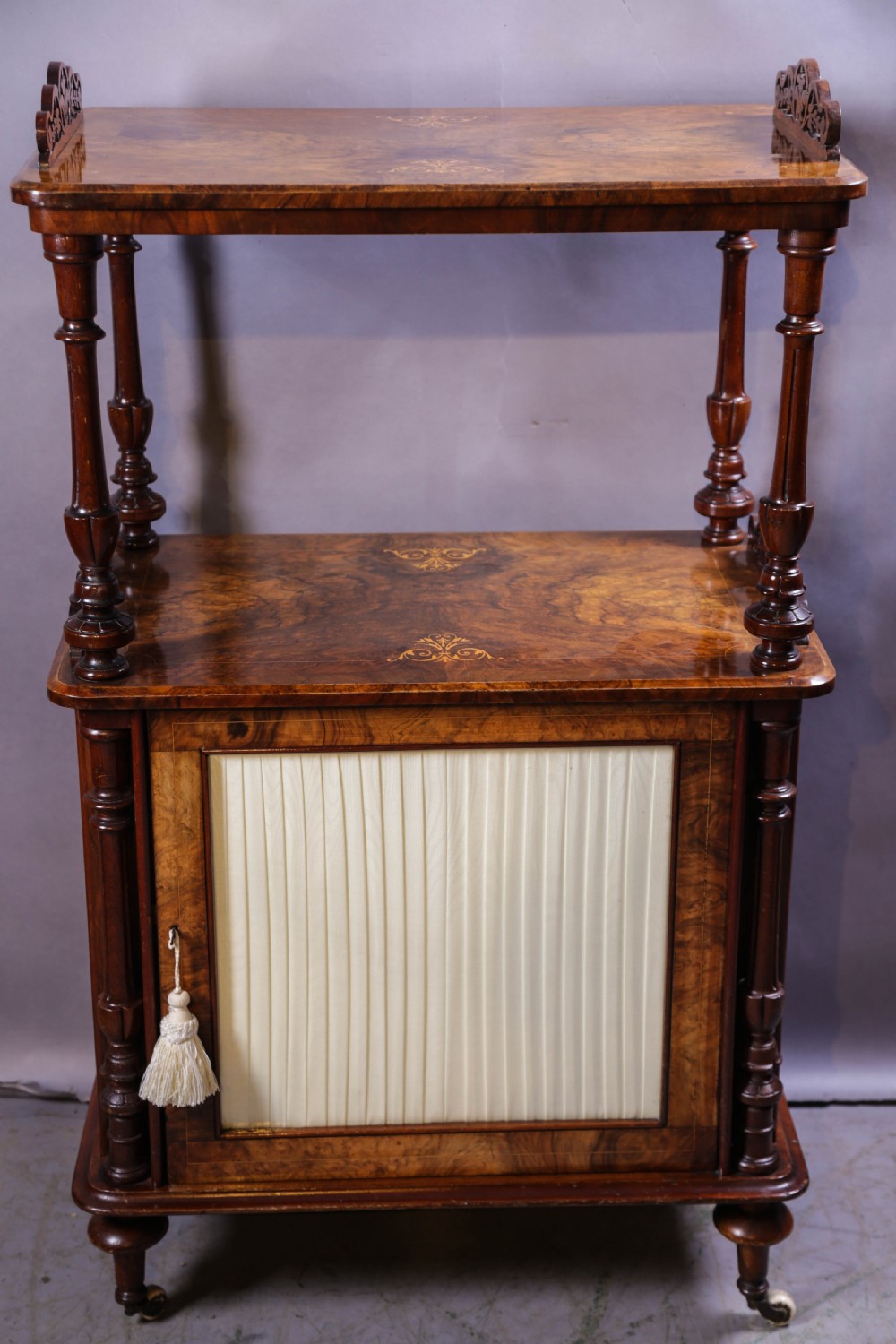 An antique Victorian burr walnut music cabinet featuring tiered shelves, marquetry inlay, turned columns, and a glazed door. View II