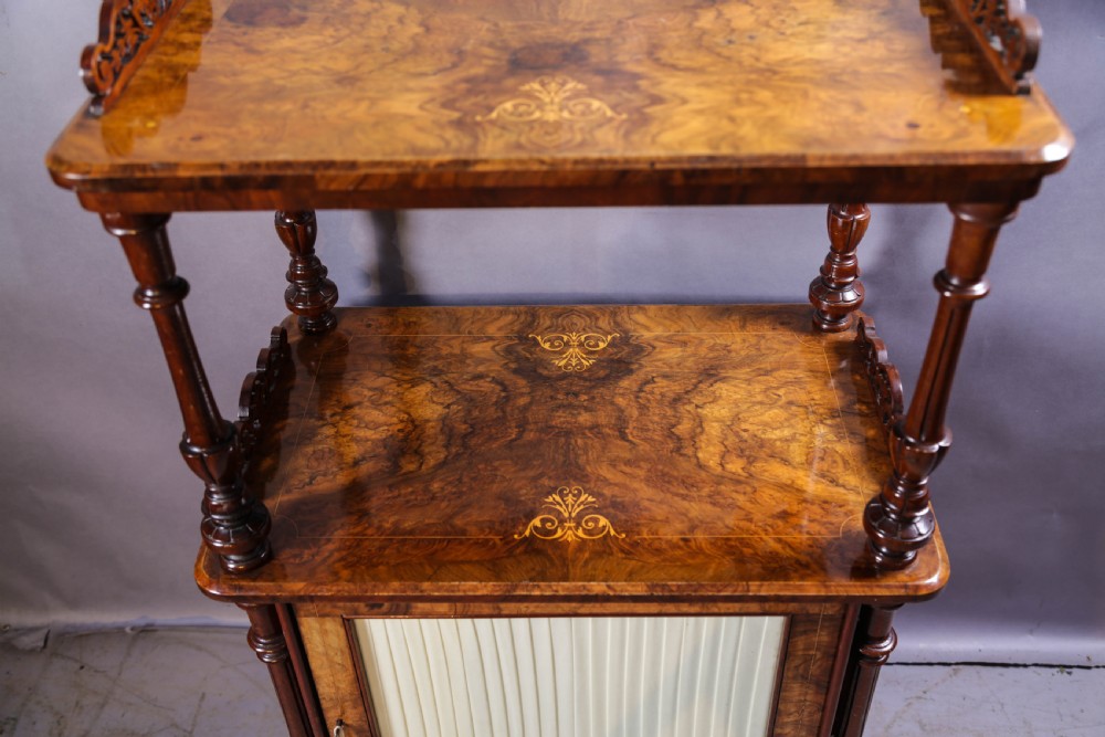 An antique Victorian burr walnut music cabinet featuring tiered shelves, marquetry inlay, turned columns, and a glazed door. View V