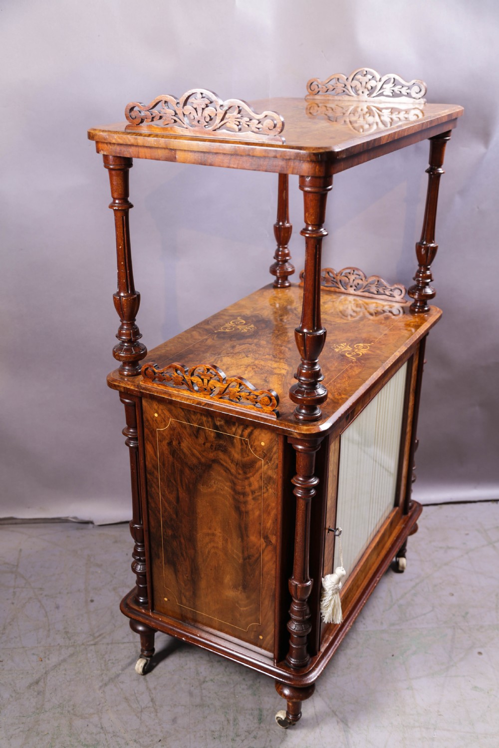 An antique Victorian burr walnut music cabinet featuring tiered shelves, marquetry inlay, turned columns, and a glazed door. View IX